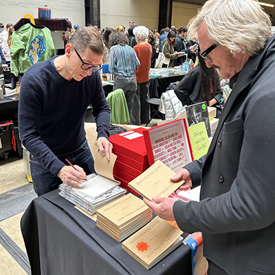 The artist signs a book at Offprint, Tate Modern 2023