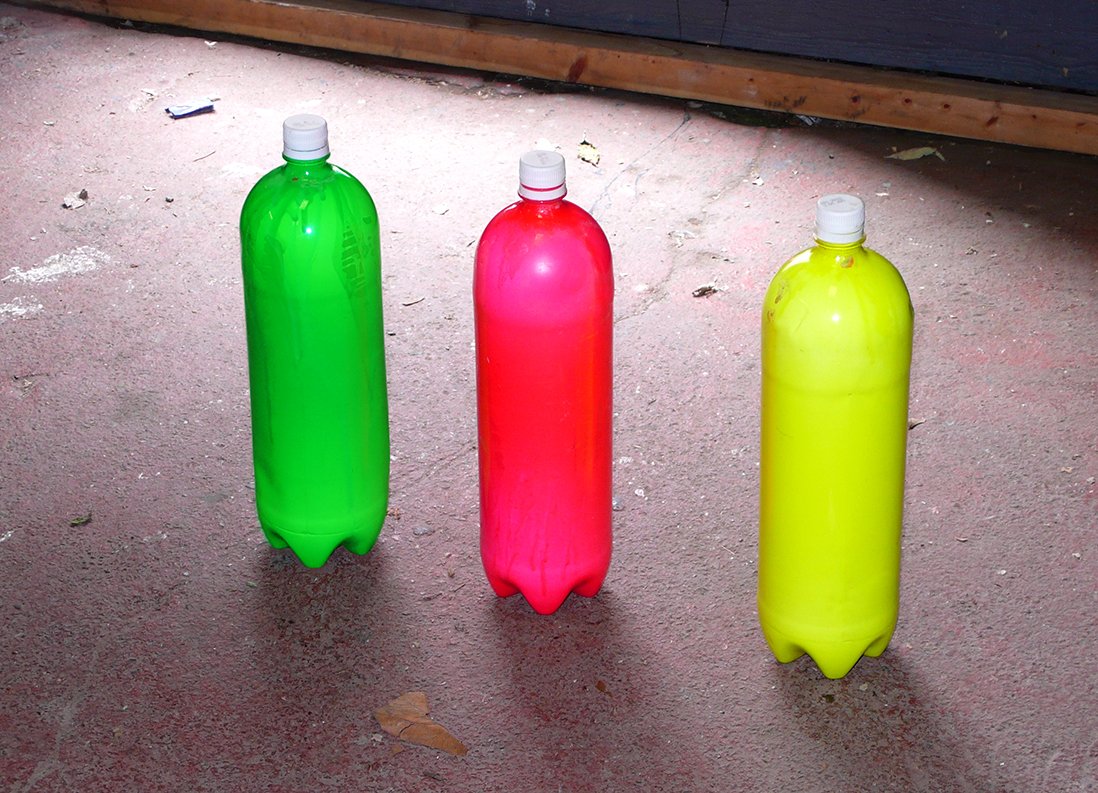 Three fluorescent-painted, 1.5 litre plastic bottles sit on the studio floor