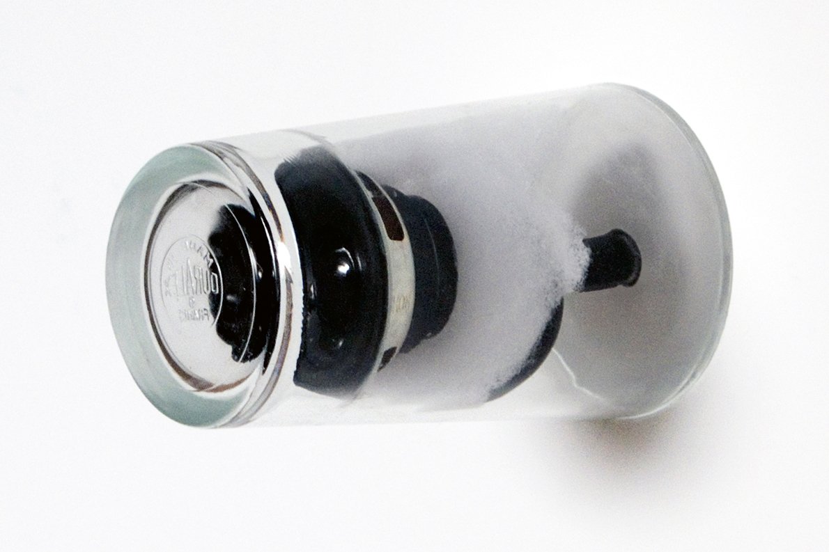 Drinking glass containing a speaker, attached to wall